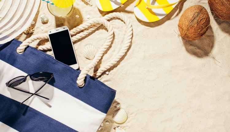 Hat, beach bag, sun glasses and glass of coconut water on a tropical beach